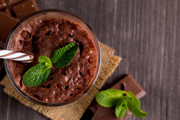 Chocolate, coffee, milk, banana shake on wooden background. Smoothie with mint. Milkshake. Protein diet. Healthy food and drink concept.