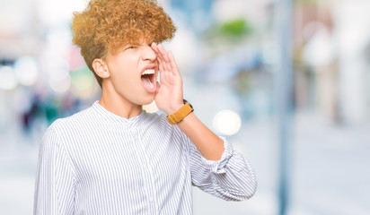 Young handsome business man with afro hair wearing elegant shirt shouting and screaming loud to...