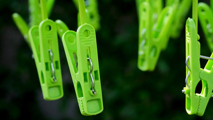 Green clothespins hanging in a garden in strong sunlight environment