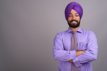 Fototapeta premium Young handsome Indian Sikh businessman wearing turban against gr