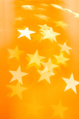 Defocused star lights on golden orange background. Graphic elements to use as backdrops or in greeting cards and other designs.