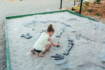 White girl have fun digging in the sand at adventure park, selective focus
