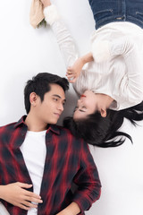 Beautiful Young couple at home,enjoy spend time together in celebration Saint Valentine's day,lay down on floor,hand hold red rose bouquet and heart pillow,happy and love motion.