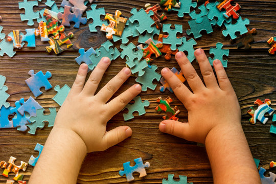 puzzles, the child's hand on wooden background. logic, pre-school education.