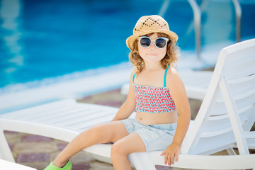 Adorable little girl sitting near the swimming pool