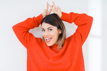 Obraz na płótnie Canvas Young woman wearing casual red sweater over isolated background Posing funny and crazy with fingers on head as bunny ears, smiling cheerful
