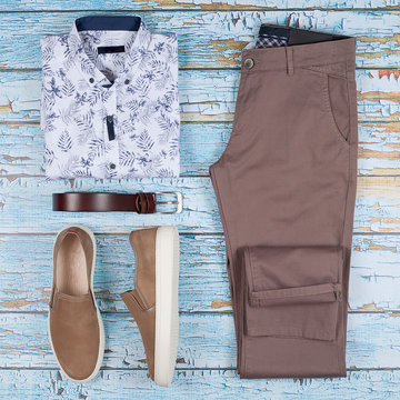 Men casual outfit. Men's shoes, clothing and accessories on wooden background - jeans, shirt, sneakers, belt. Top view. Flat lay