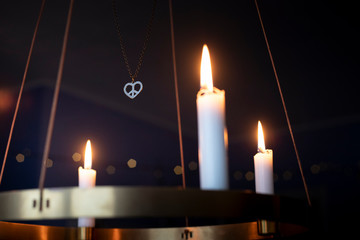 Peace heart symbol necklace and candles glowing on advent chandelier.