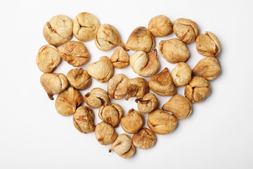 Heart shaped heap of dried figs on white background, top view. Healthy fruit