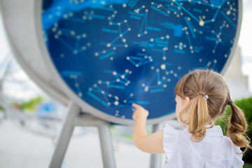 MOSCOW, RUSSIA - JULY 6: Exhibition in Moscow Planetarium. Little girl looking at the exhibits of the one of the world`s largest planetarium, star chart - obrazy, fototapety, plakaty