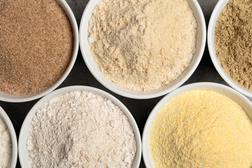 Bowls with different types of flour on table, top view