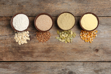 Flat lay composition with different types of flour and seeds on wooden background. Space for text
