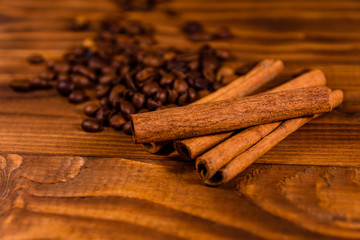Pile of the coffee beans and cinnamon sticks on wooden table