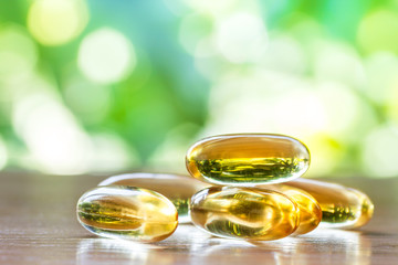 fish oil capsules on wooden table with natural background
