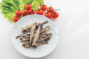 sardine accciughe salate in piatto bianco con insalata e pomodorini