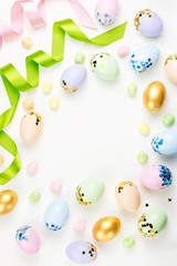 Fototapeta na wymiar Festive Easter background with decorated eggs, flowers, candy and ribbons in pastel colors on white. Copy space