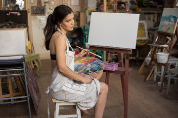 Professional Woman artist painting picture in art studio.