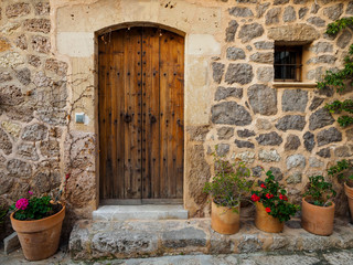 Fototapeta na wymiar Rustic door surrounded by pots with plants in Valldemossa, Mallorca