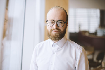 Close up portrait of young bearded man in casual wearing glasses and looking at the camera
