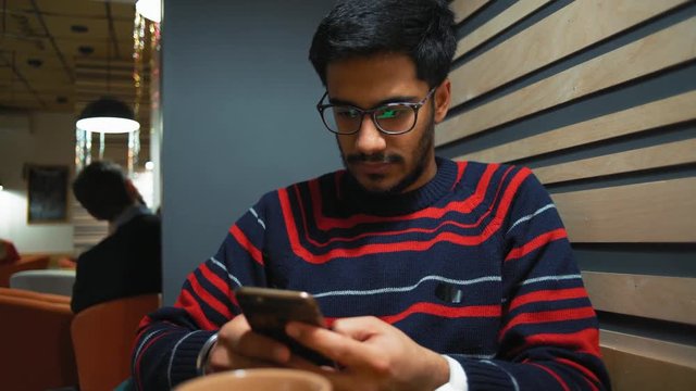 Close-up, Indian Guy Communicates with Smartphone in Cafe