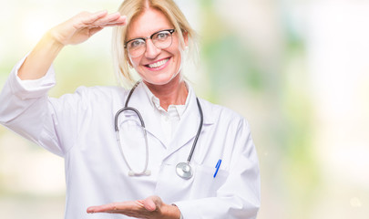 Middle age blonde doctor woman over isolated background gesturing with hands showing big and large size sign, measure symbol. Smiling looking at the camera. Measuring concept.