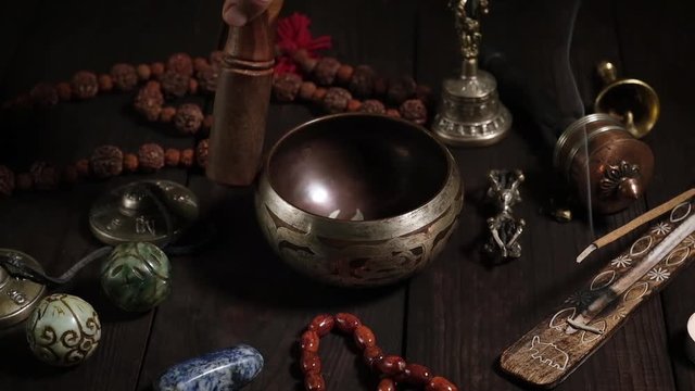 singing bowl, prayer beads, prayer drum, stone balls and other Tibetan religious objects for meditation and alternative medicine on a brown wooden background,