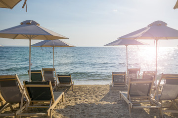 Umbrellas and chairs arranged in the row with blue sea water in background