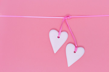 Two white hearts together on pink background. Holiday concept for wedding or Valentine’s Day.