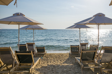 Umbrellas and chairs arranged in the row with blue sea water in background