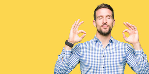 Handsome business man with blue eyes relax and smiling with eyes closed doing meditation gesture with fingers. Yoga concept.