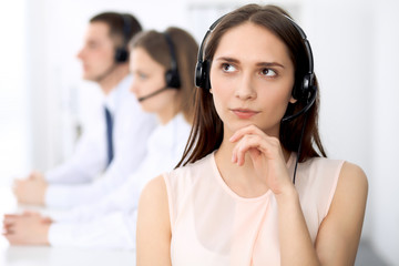 Call center operators. Focus on young cheerful smiling woman in headset. Business and customer service concepts