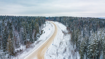 Aerial view of forest covered with snow, road in winter time