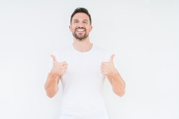 Young handsome man wearing casual white t-shirt over isolated background success sign doing positive gesture with hand, thumbs up smiling and happy. Looking at the camera with cheerful expression