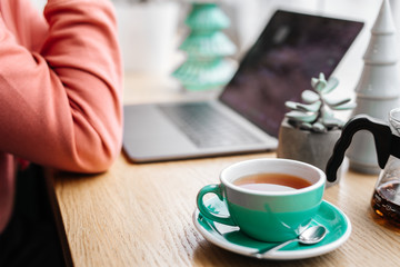 Red tea and man working at his laptop in cafe, green tea, plant, screen, hands.