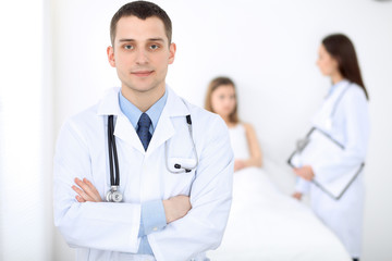 Fototapeta premium Medicine doctor standing and smiling on the background with patient in the bed