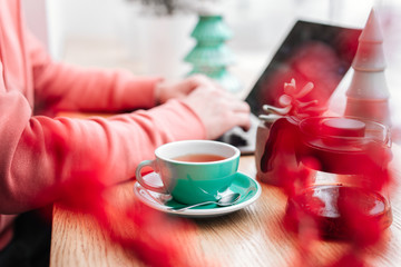 Red tea and man working at his laptop in cafe, green tea, plant, screen, hands.