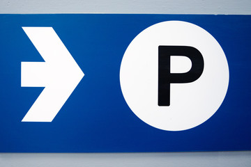 blue parking sign with white arrow and black capital P on white background