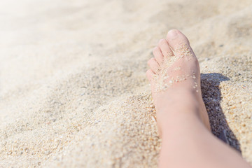 Close up of female feet on a hot sand on the beach