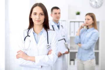 Fototapeta premium Young beautiful female doctor smiling on the background with patient in hospital