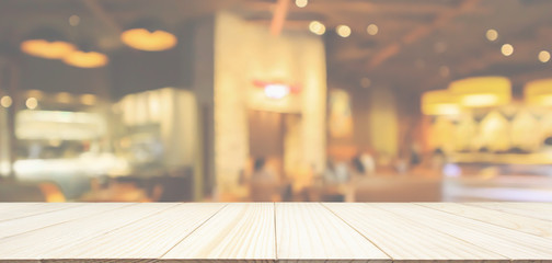 Wood table top with Restaurant cafe or coffee shop interior with people abstract defocused blur background