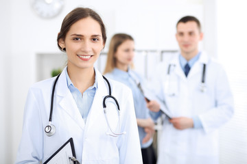 Young beautiful female doctor smiling  on the background with patient  in hospital