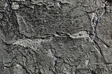 Collapsing layer of black paint on the concrete surface. Abstract background. Close up