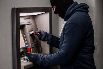 Thief. Hacker stealing money from ATM machine. Phishing, ATM skimming