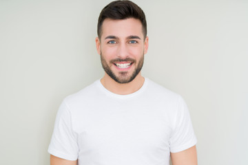 Young handsome man wearing casual white t-shirt over isolated background with a happy and cool smile on face. Lucky person.