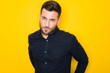 Obraz premium Young handsome man possing and modeling over yellow isolated background