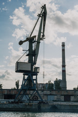 Portal crane on river bank against sky