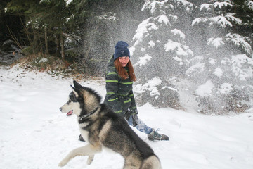 Husky dog runs in the woods with a girl. Play in the snow. Winter fun with a pet