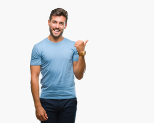 Young handsome man over isolated background smiling with happy face looking and pointing to the side with thumb up.