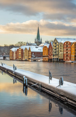 Old houses and magazines by Nidelva river in Trondheim, Nidarosdomen Cathedral in back.