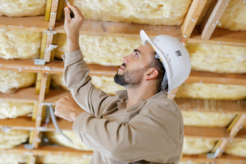 builder drives screws into ceiling